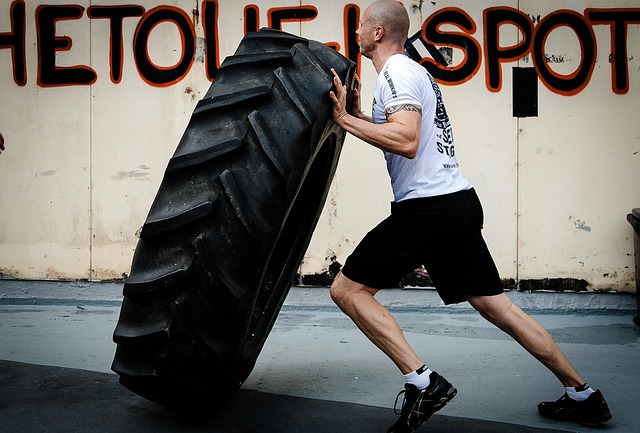 Athlete powering through a tire flip, representing raw strength training at Iron Grit.